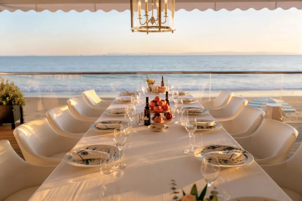 An outdoor dining table set for guests at Rosewood Miramar Beach, overlooking the ocean.