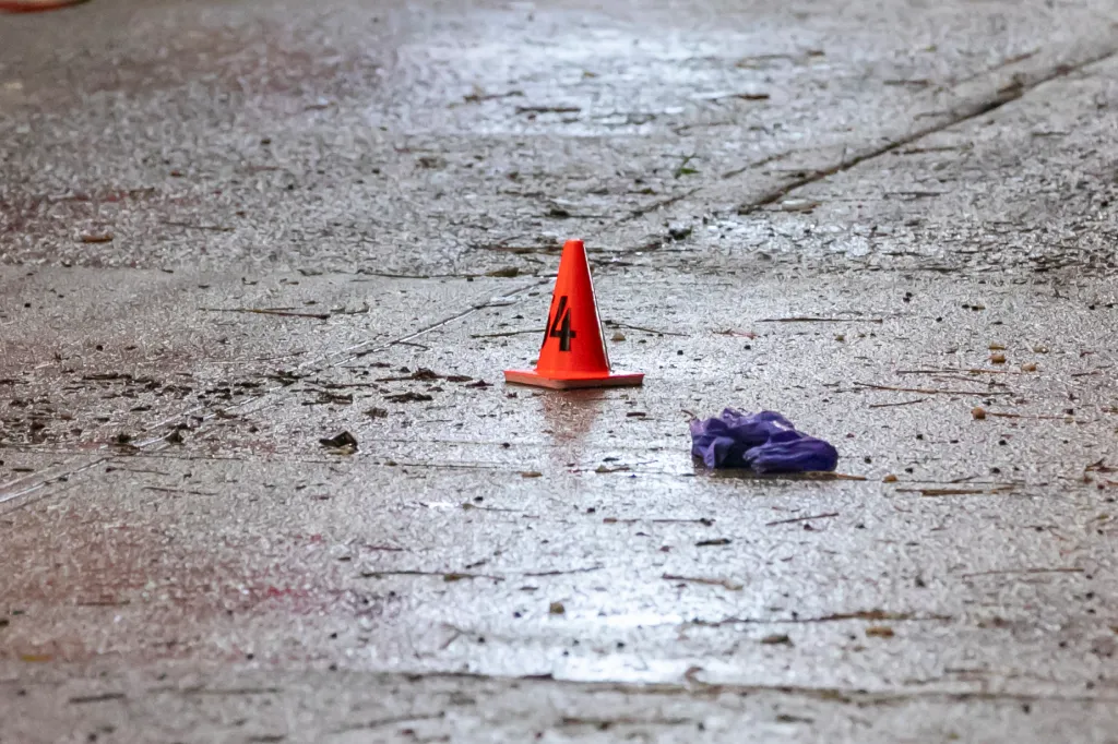 Crime scene marker 14 and a purple glove on a wet sidewalk.