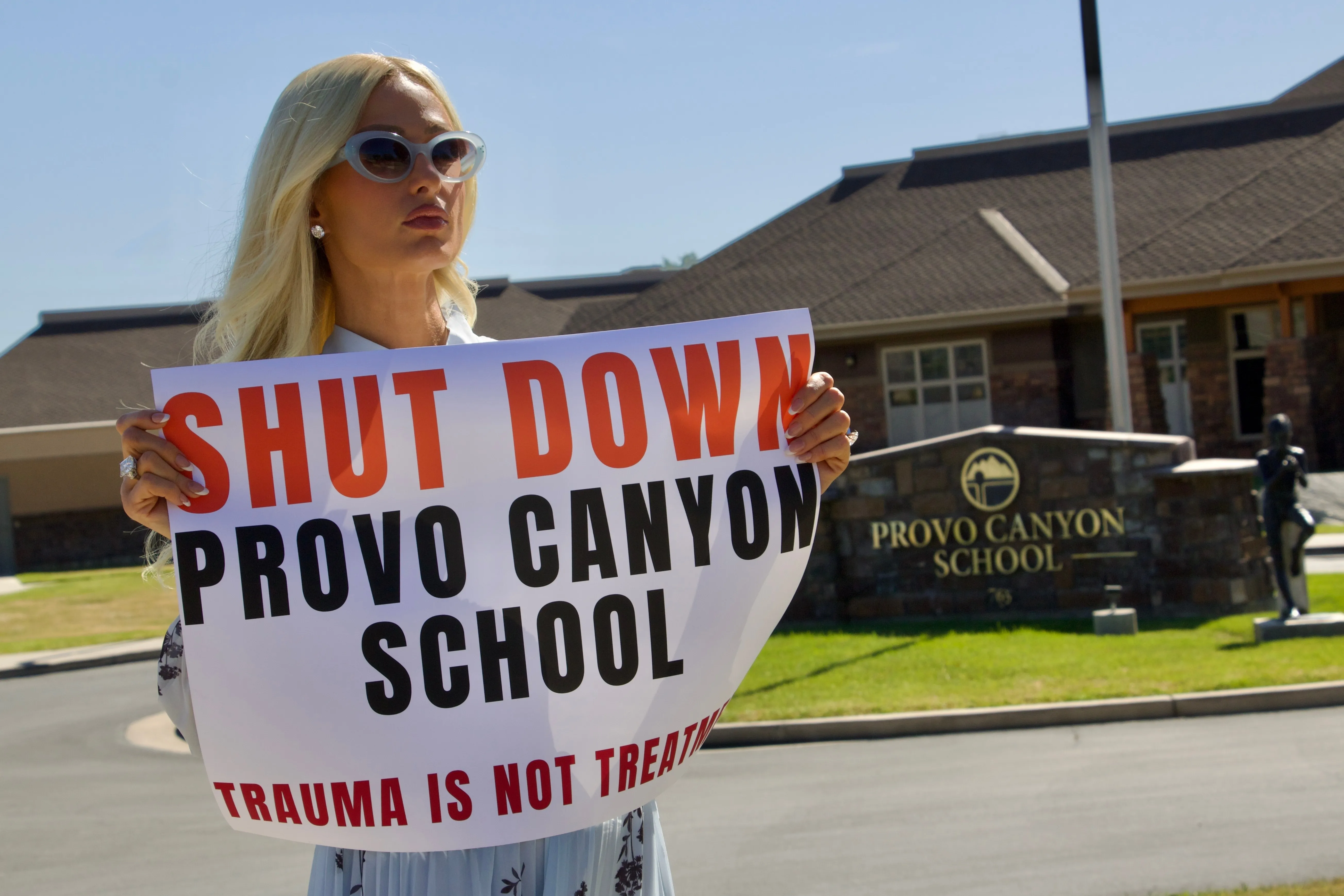 Paris Hilton protests outside the Provo Canyon School, holding a 