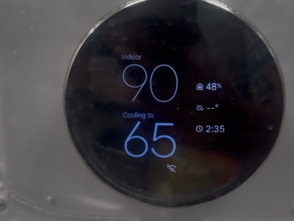 A smart thermostat display showing an indoor temperature of 90 degrees and