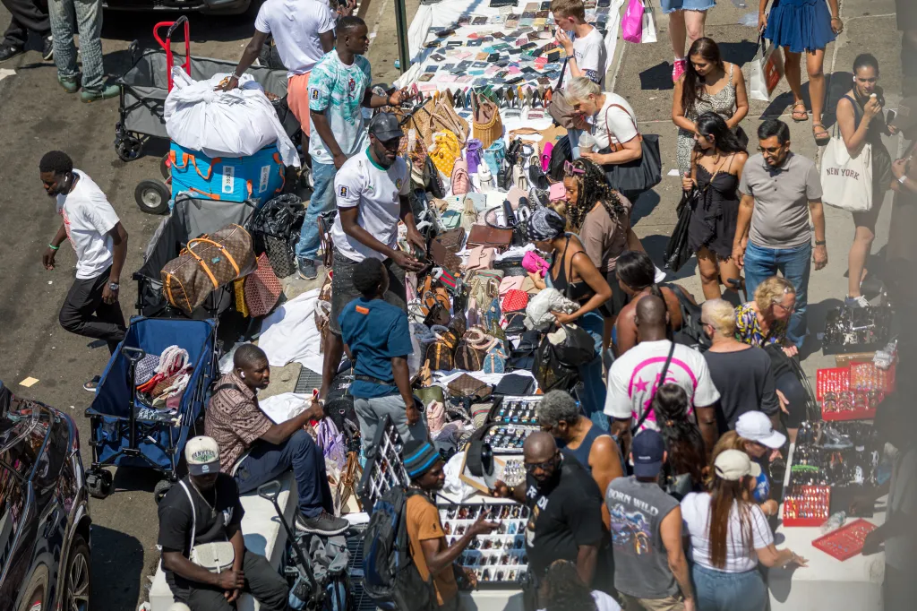 People purchasing items from street vendors on Broadway and Canal in New York City.