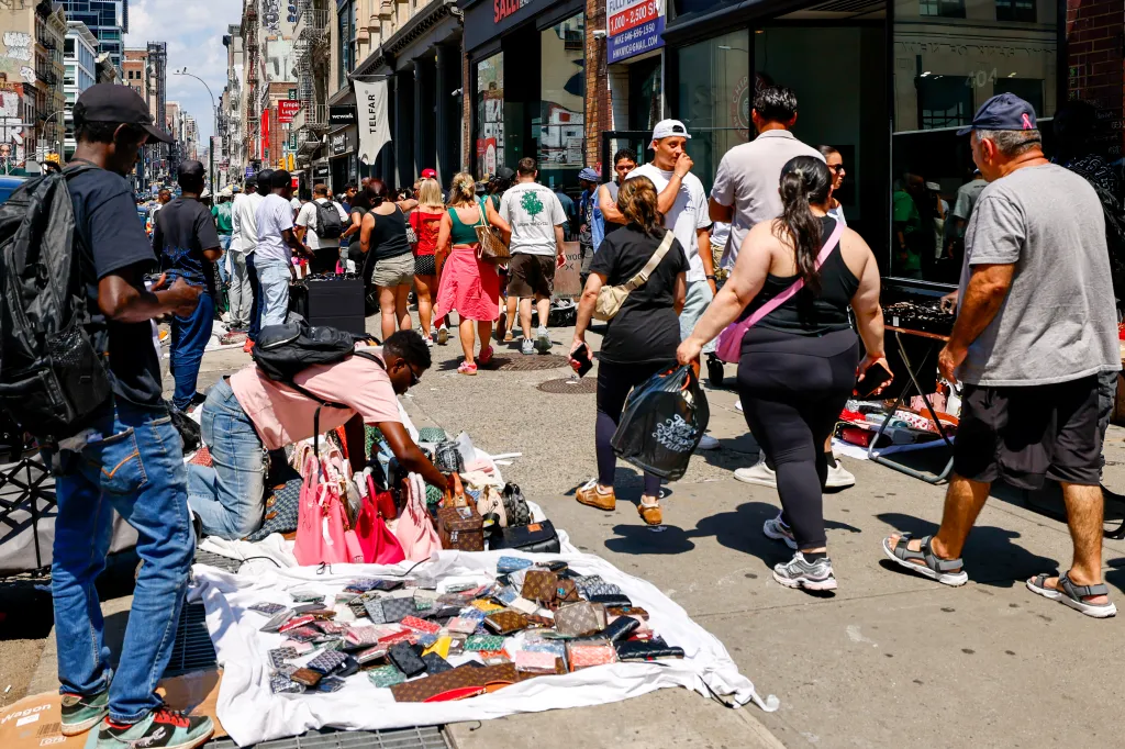 People buying items from street vendors on Broadway and Canal in New York City.