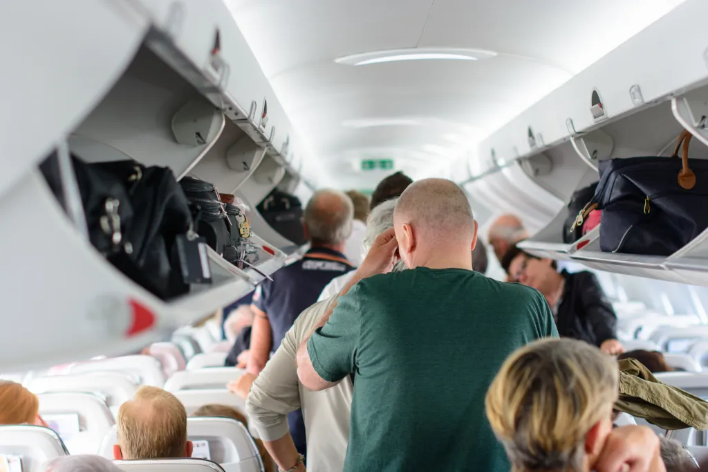 People standing in the aisle of an airplane waiting to disembark.