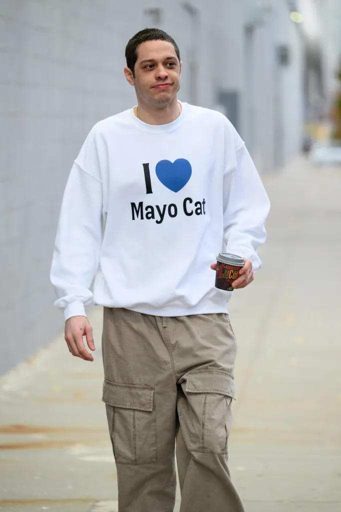 Pete Davidson walking while wearing a white 