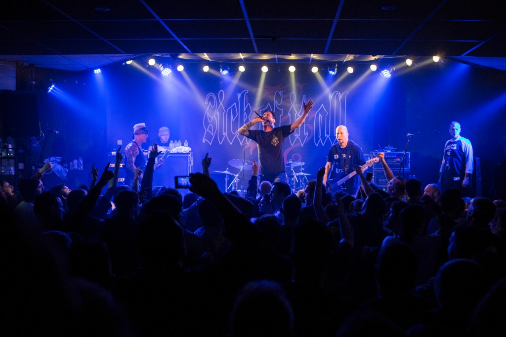 Sick Of It All performing on stage under blue lights with a crowd in front.
