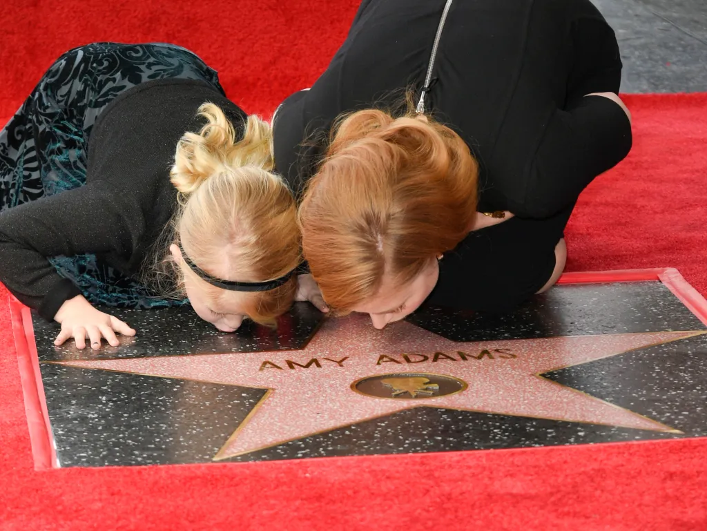 Amy Adams and daughter Aviana Le Gallo crouch over Amy Adams' star on the Hollywood Walk of Fame.