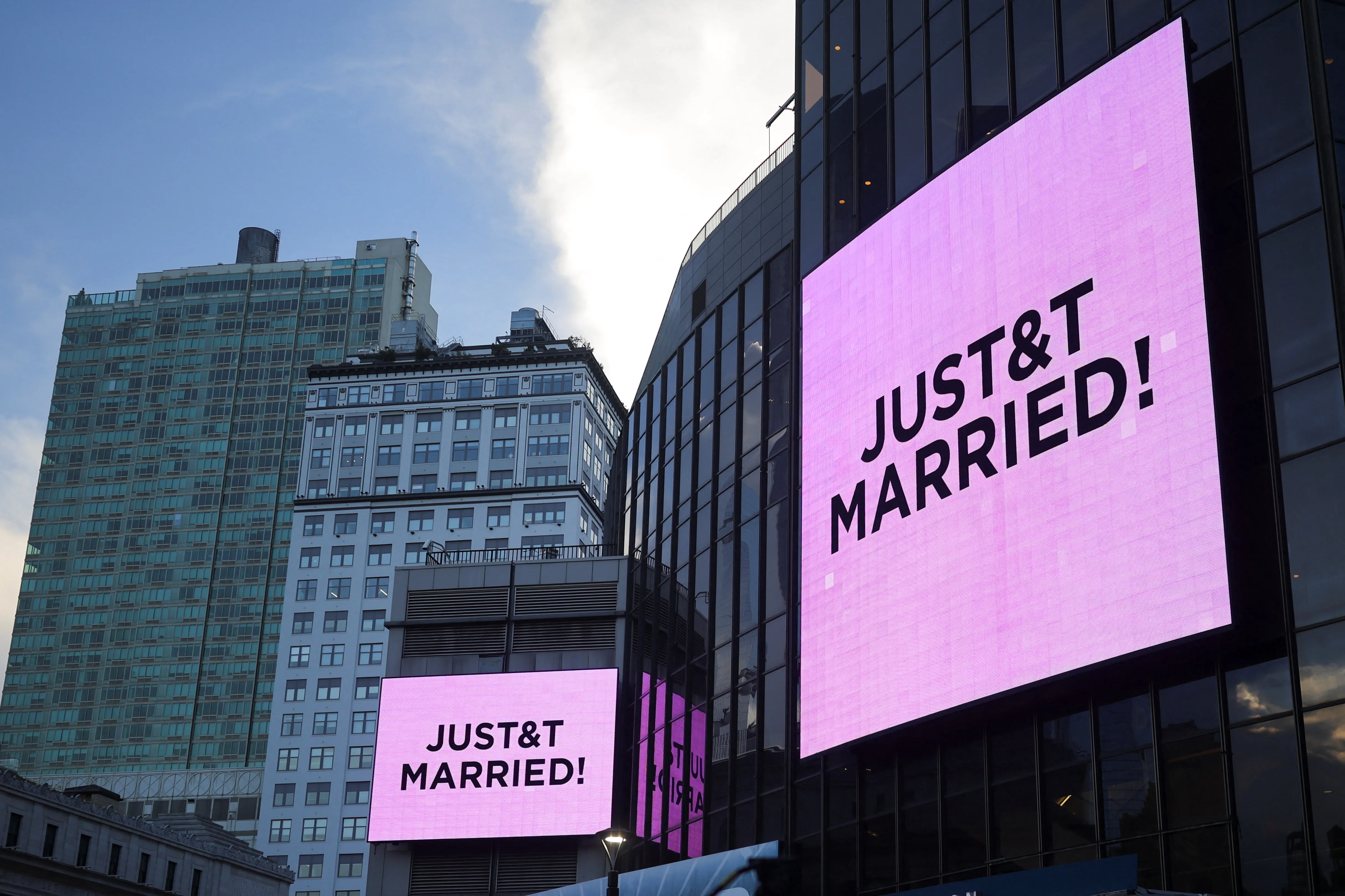 Two large digital screens on a building in New York City display 