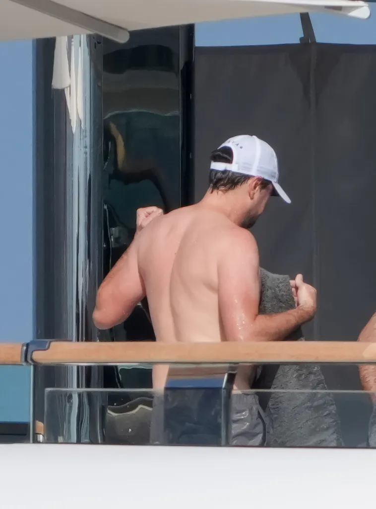 Leonardo DiCaprio, shirtless and wearing a white cap, on a luxury yacht in St. Tropez.