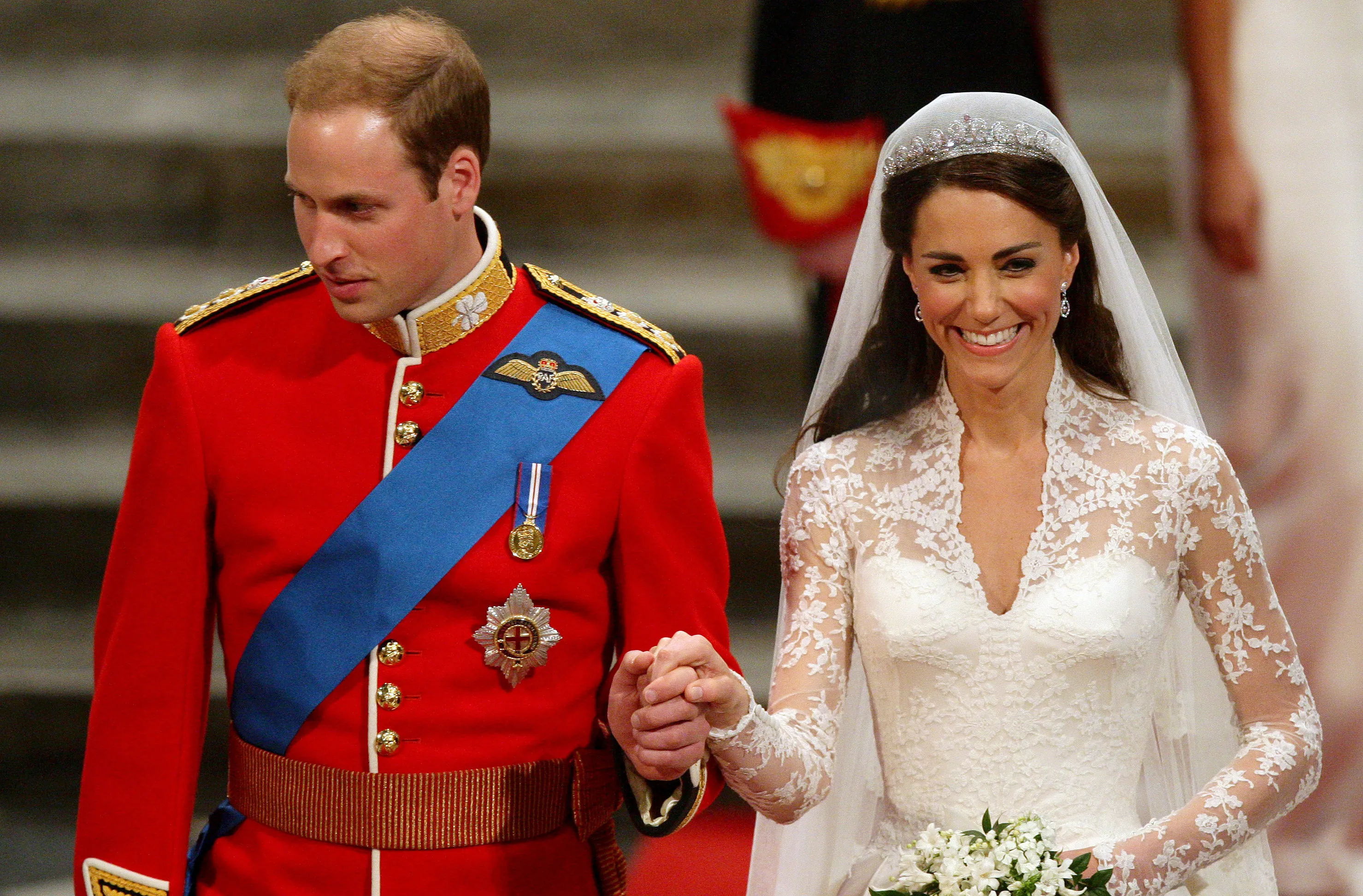 Prince William in military uniform and Catherine Middleton in a white wedding gown holding hands.