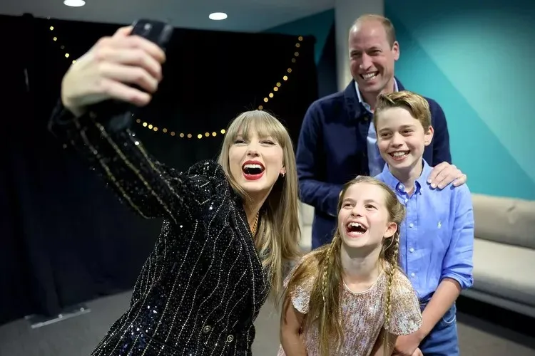 Taylor Swift taking a selfie with Prince William, Prince George, and Princess Charlotte, all smiling and laughing.