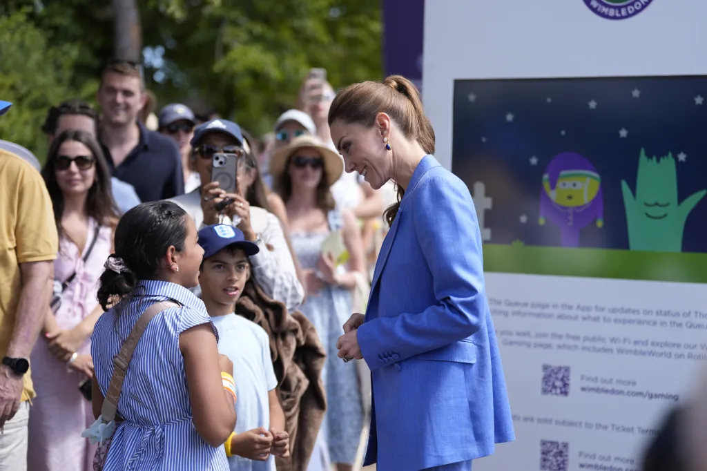Catherine, Princess of Wales, in a blue pantsuit, smiling at two children at the Wimbledon Tennis Championships.