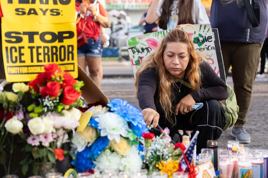 A woman lighting a candle at a memorial to Lorenzo Salgado Araujos.