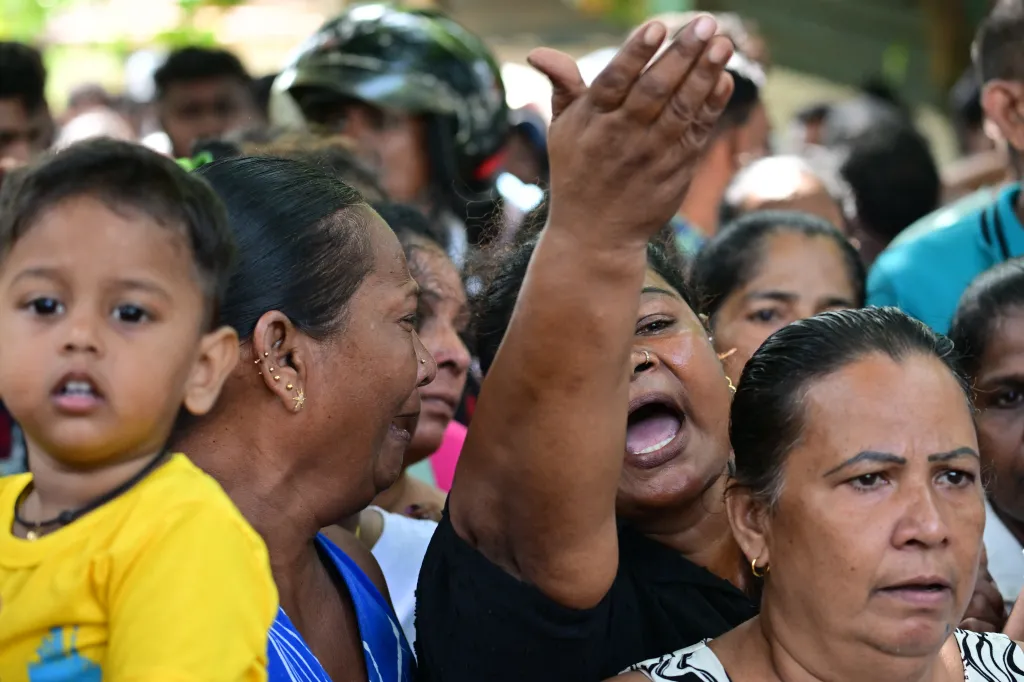 Relatives of victims killed in clashes between inmates in a Sri Lankan jail grieve, with one woman raising her arm in anguish.