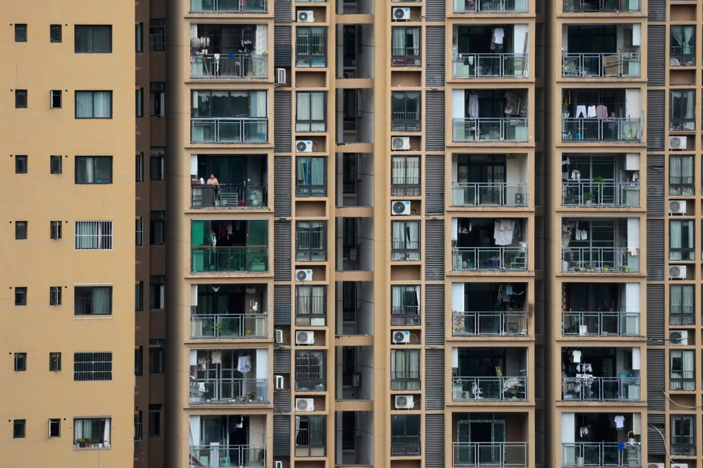 A resident stands on a balcony of a residential building, overlooking a landslide search operation in Pengshui County, China.