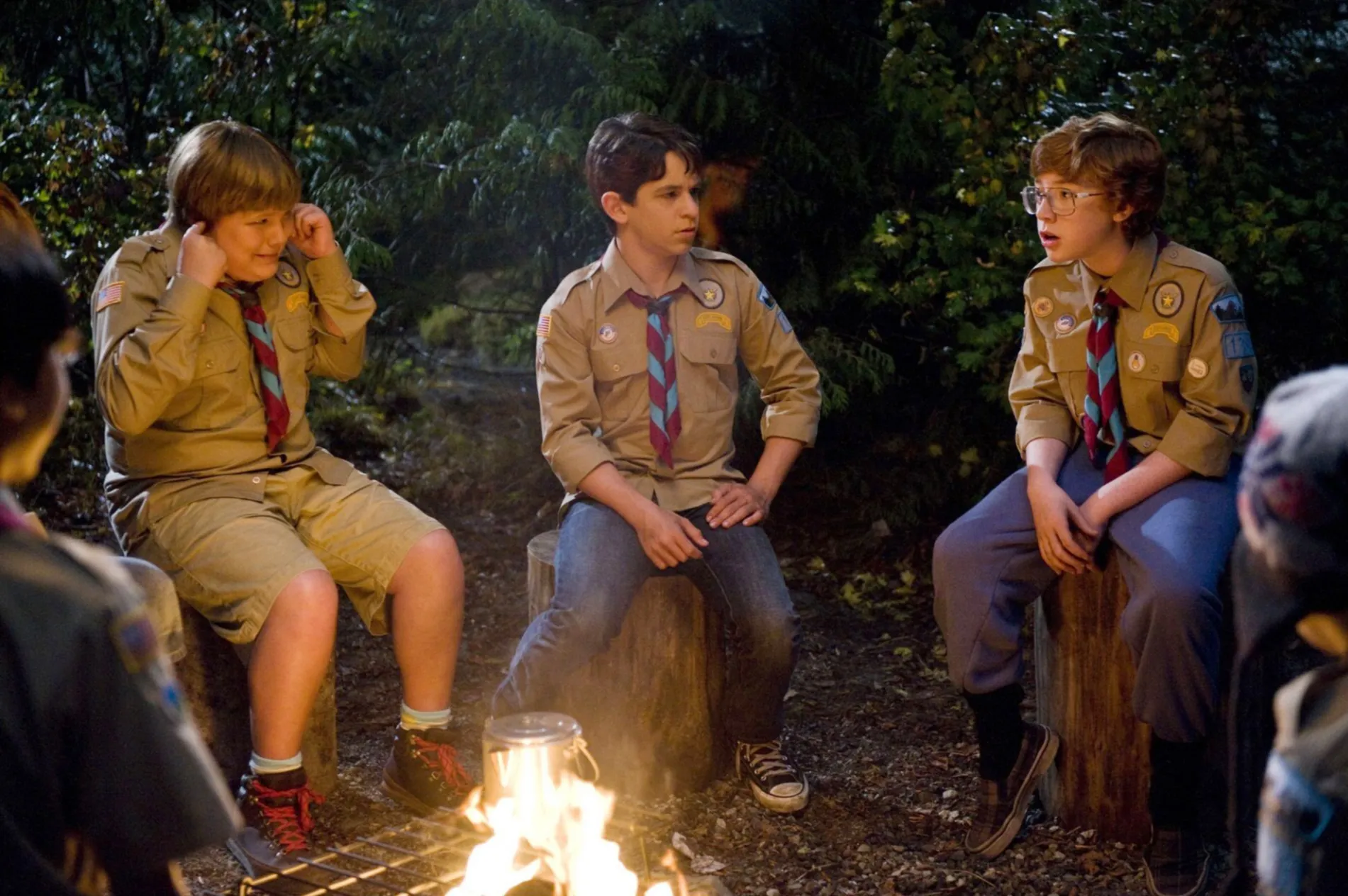 Robert Capron, Zachary Gordon, and Grayson Russell sitting around a campfire in their summer camp uniforms.