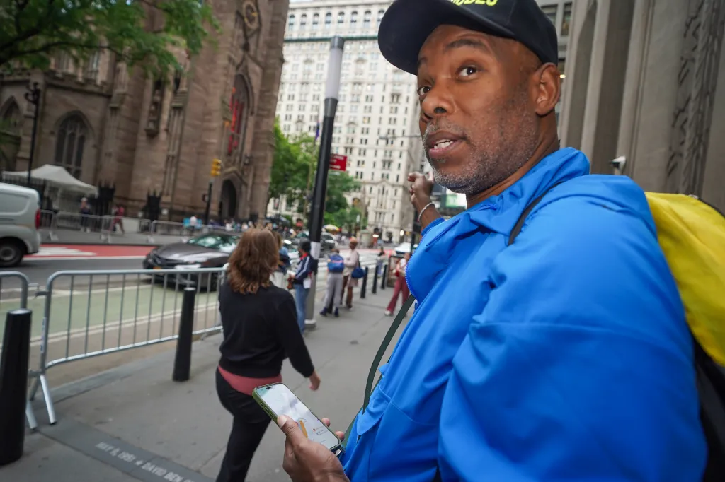 Roberts Samuel, founder of Same Ole Line Dudes, holds a phone showing a map for a customer's viewing spot of the Knicks Championship Parade.
