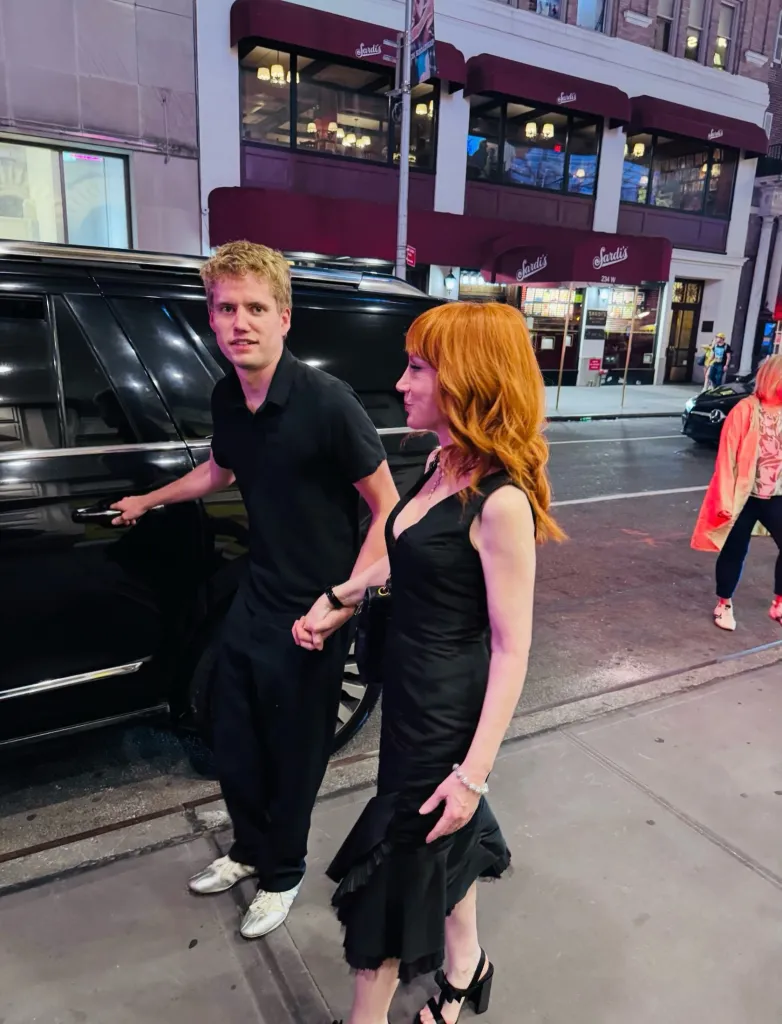 Kathy Griffin and her new boyfriend holding hands, standing next to a black car.