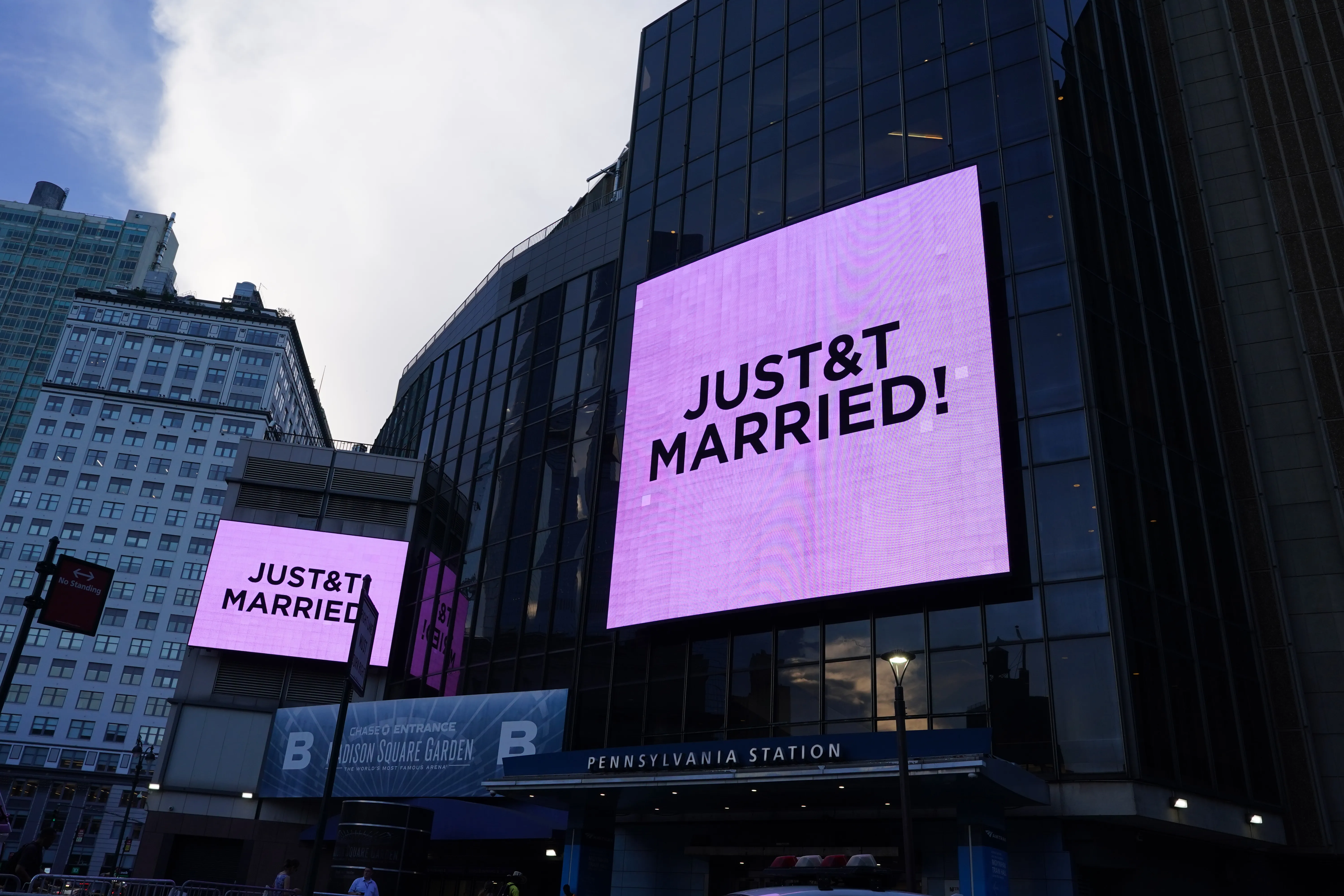 Two large outdoor screens on Madison Square Garden display the text 