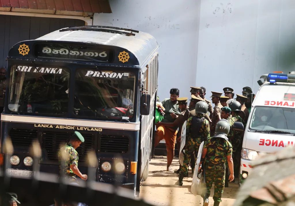 Security personnel escort a prisoner onto a bus at Negombo Prison after a riot.