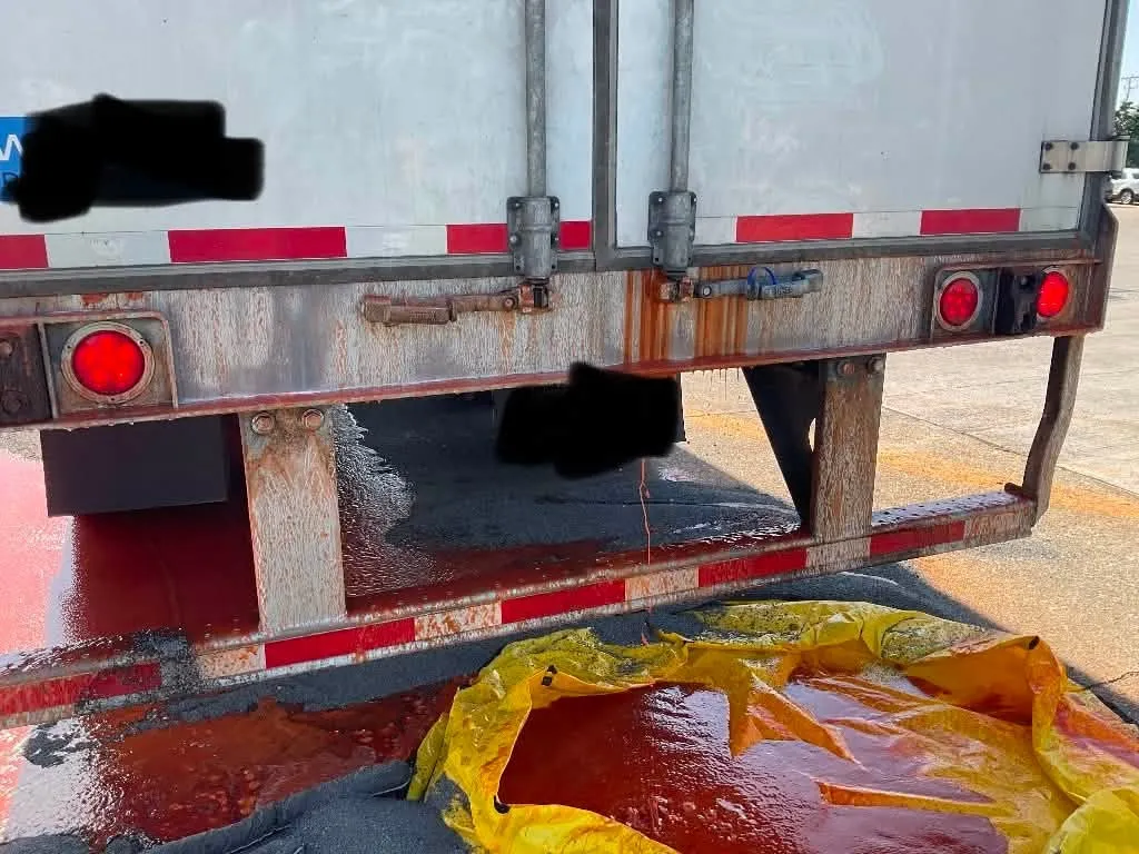 Frank's RedHot sauce spilling from the back of a semi-truck onto the ground and a yellow tarp.
