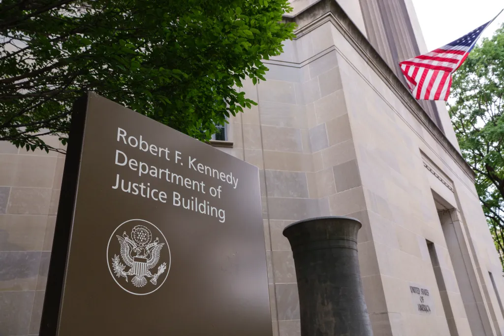 Sign for the Robert F. Kennedy Department of Justice Building, with an American flag hanging from the building.