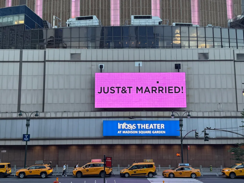 A large pink electronic billboard on the Madison Square Garden building reads 