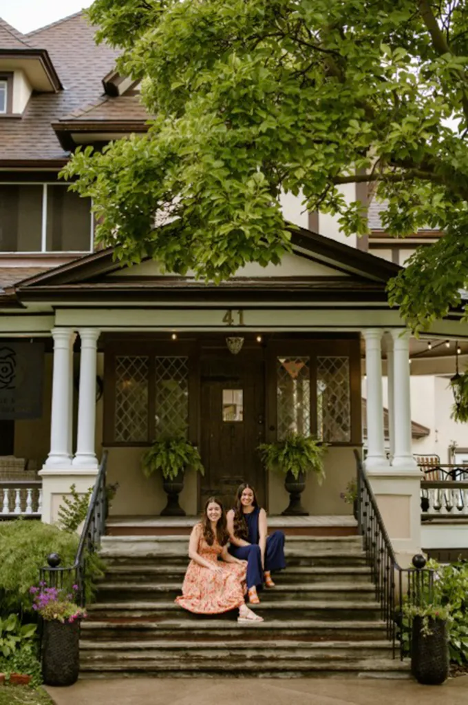 Kristen and Kathryn Groom sit on the steps of the Rose Manor.