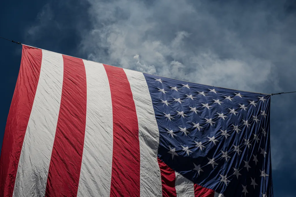 Smoke rises behind an American flag at the