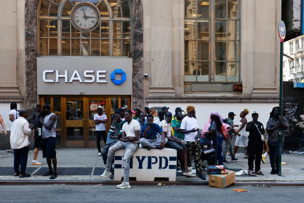 Street vendors in front of a Chase bank in New York City watching police confiscate merchandise.