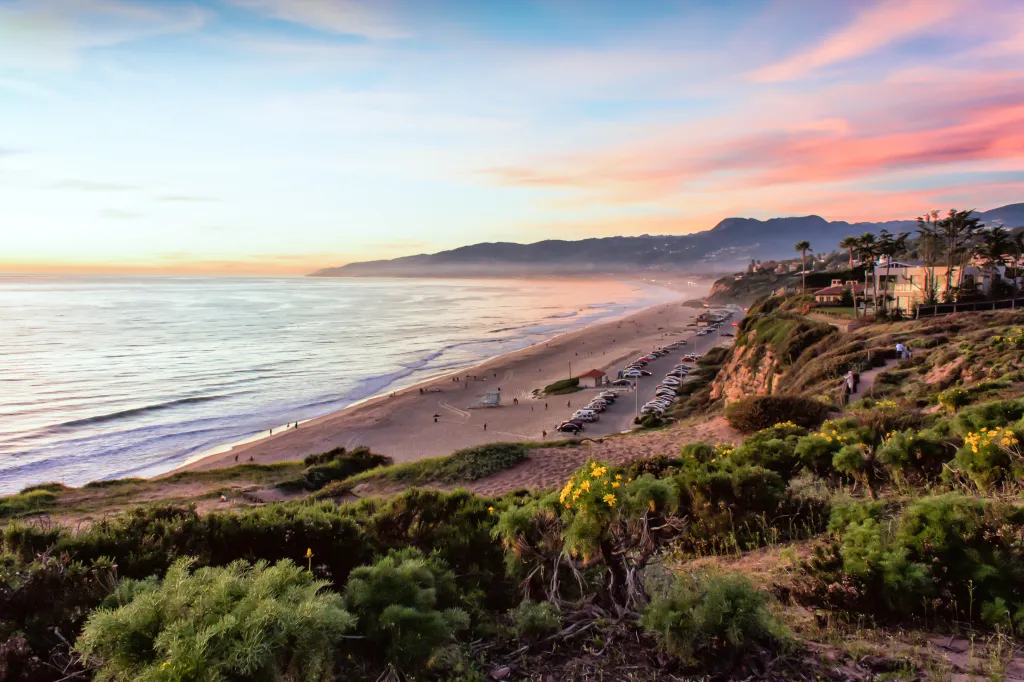 Sunset over Santa Monica Bay with people on the beach and cliffs.