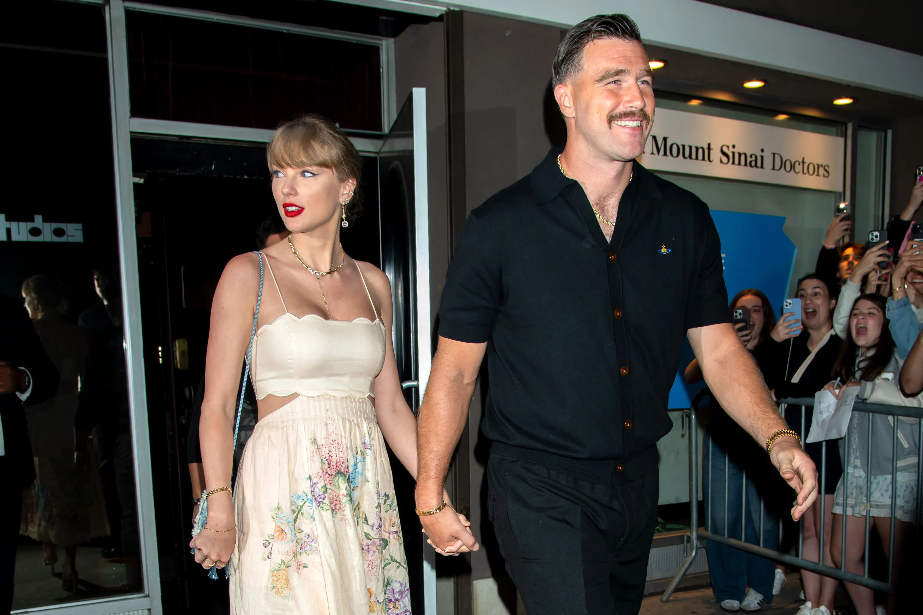 Taylor Swift and Travis Kelce hold hands while leaving Karen Elson's wedding.