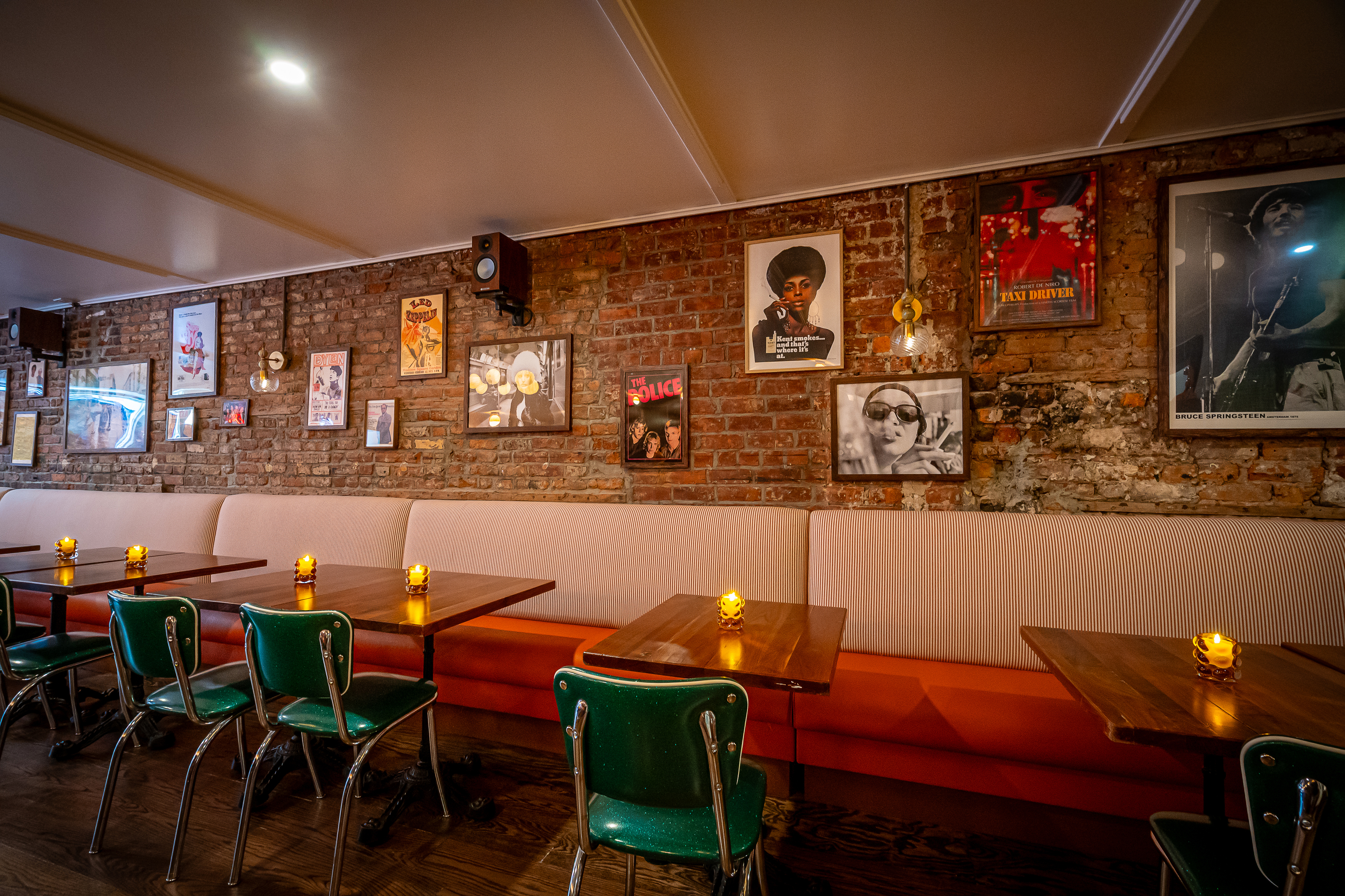 Interior of a pizza joint with an exposed brick wall adorned with various posters, including