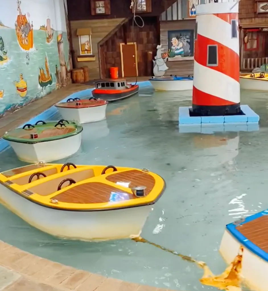 Several boats in murky, brown water at an amusement park.