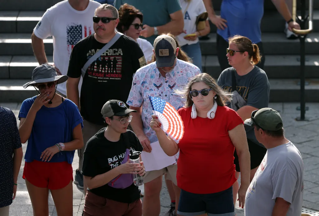 A tourist uses a patriotic fan to cool off while waiting in line to enter the U.S. Capitol Building.