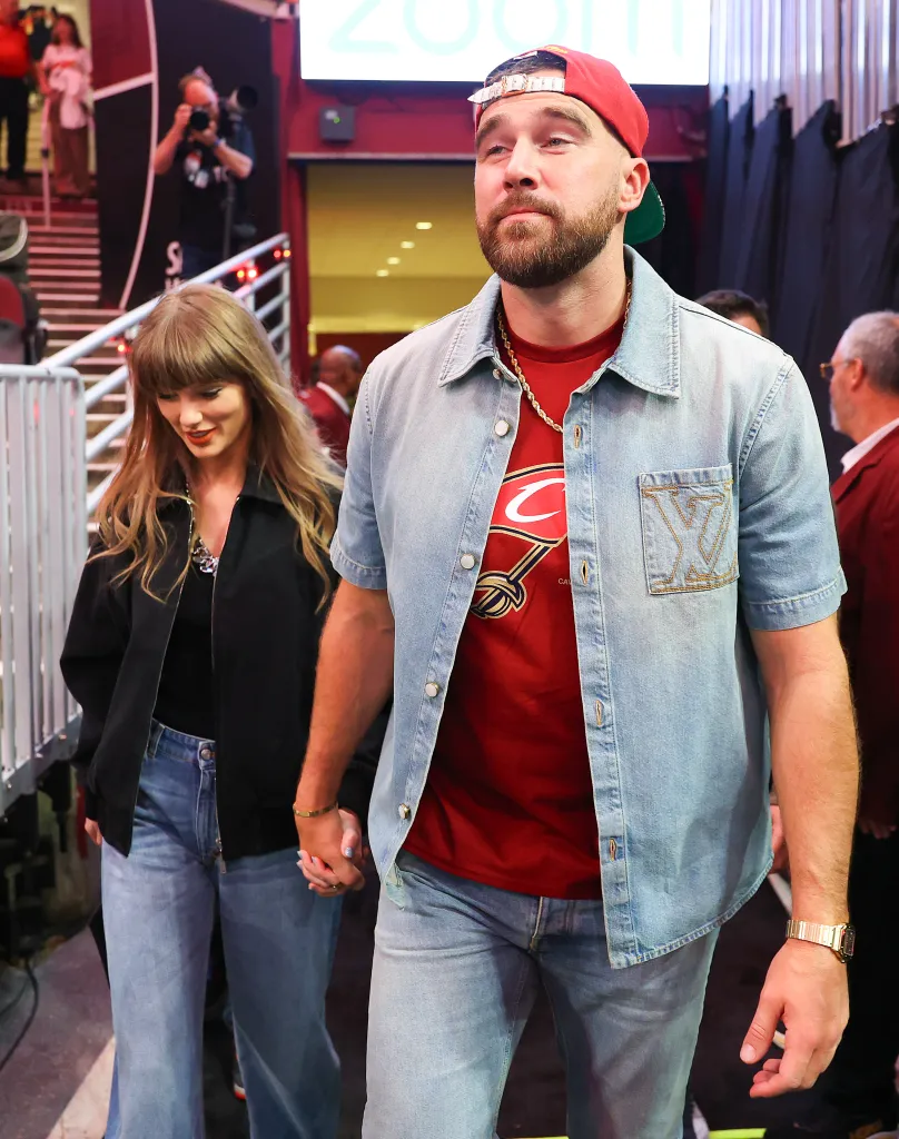Singer Taylor Swift and Travis Kelce of the Kansas City Chiefs holding hands while attending an NBA basketball game.