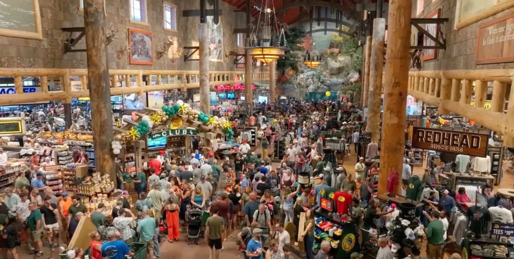 A large, crowded Bass Pro Shops store filled with shoppers.