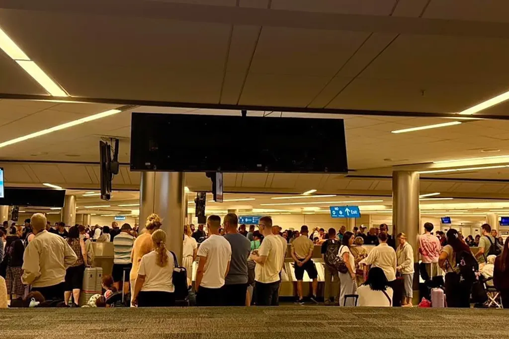 Travelers wait at baggage claim during a delay at Orlando International Airport on June 27, 2026.