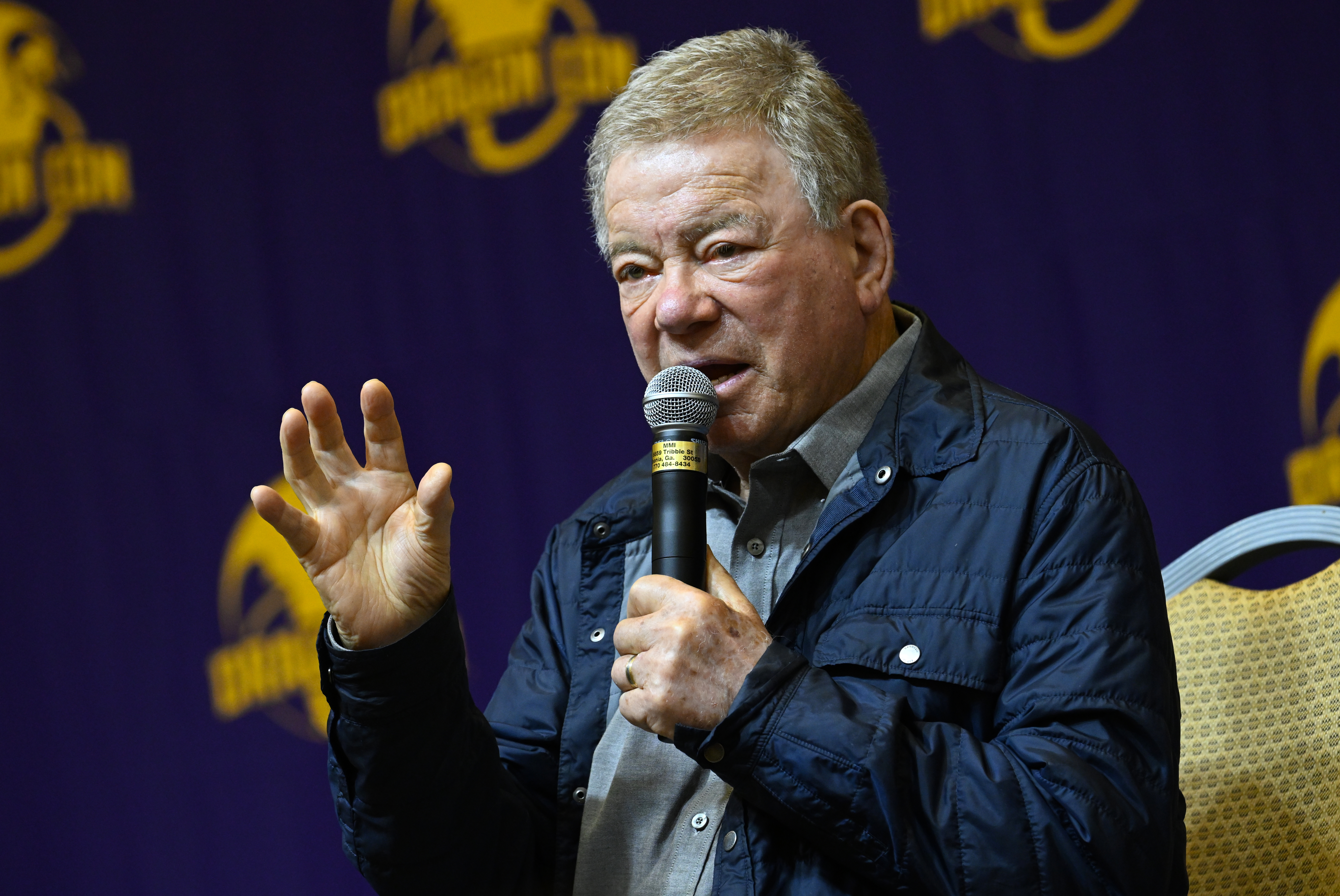William Shatner speaking onstage into a microphone at Dragon Con.