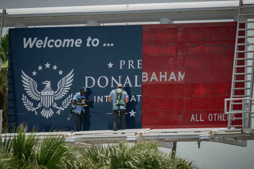 Two workers installing signage at Palm Beach International Airport, featuring a blue section with 