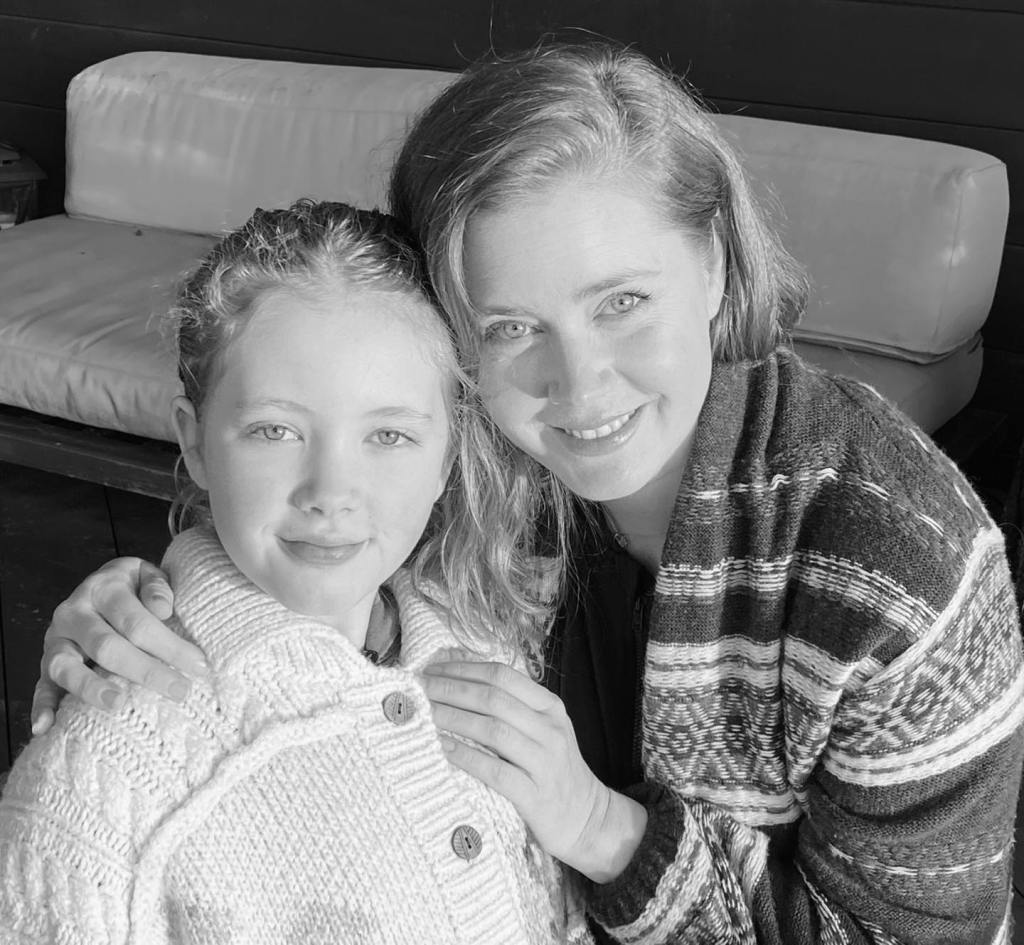Amy Adams and her daughter Aviana, with Amy's arm around Aviana, smiling at the camera.