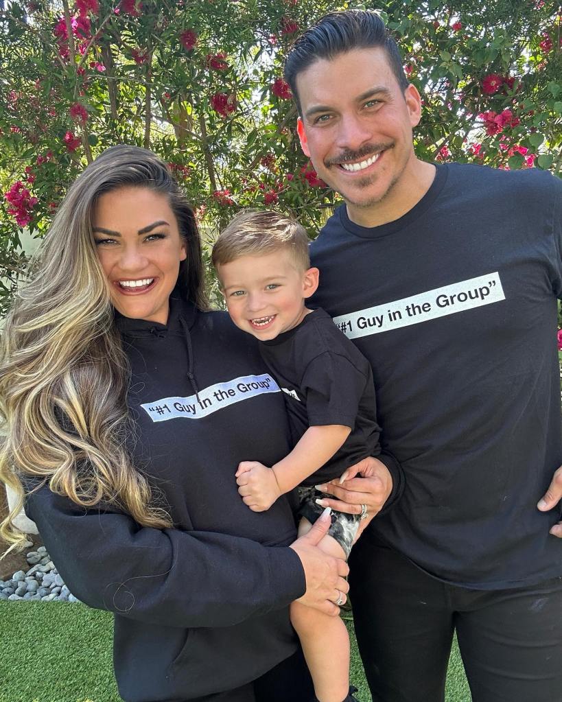 Brittany Cartwright and Jax Taylor holding their child, all wearing black shirts that say