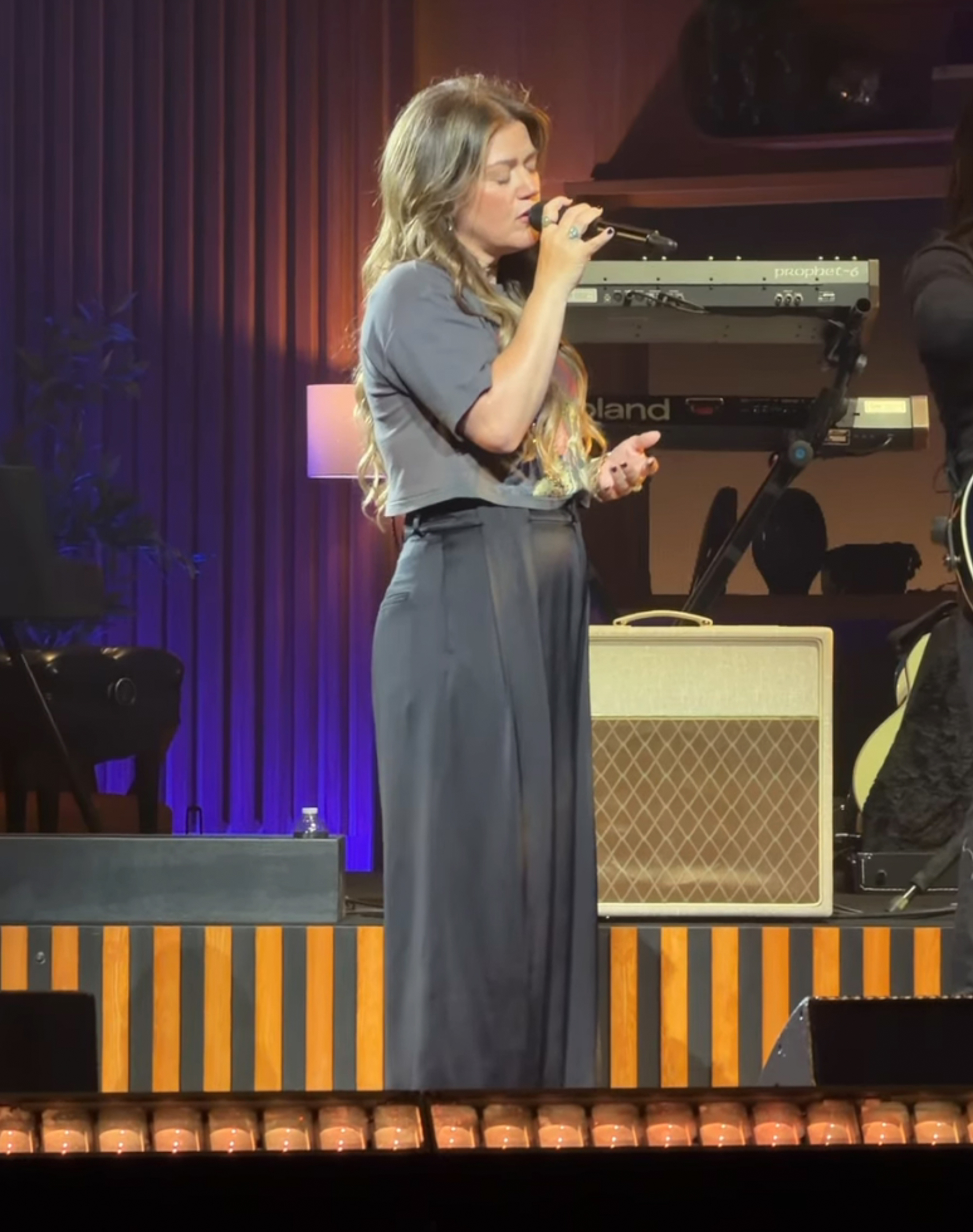 Kelly Clarkson singing into a microphone on stage.