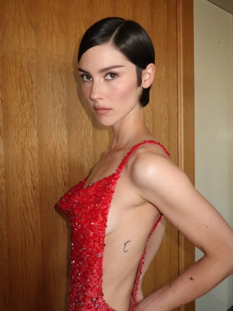 Gracie Abrams in a red sequined dress, posing for a photo.