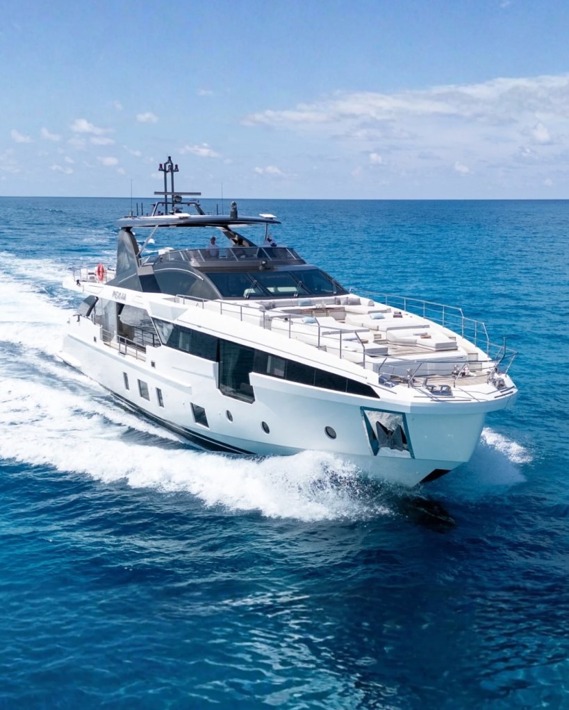 White yacht with black accents cutting through blue water.