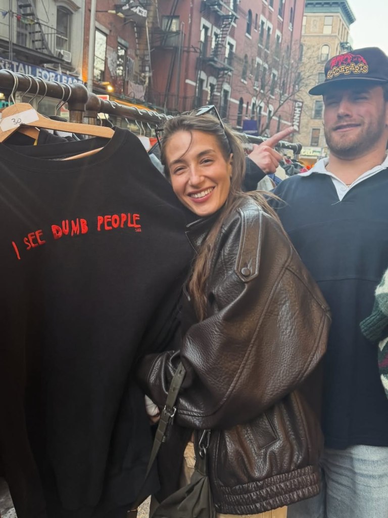 Amanda Batula holding up a black sweatshirt that says