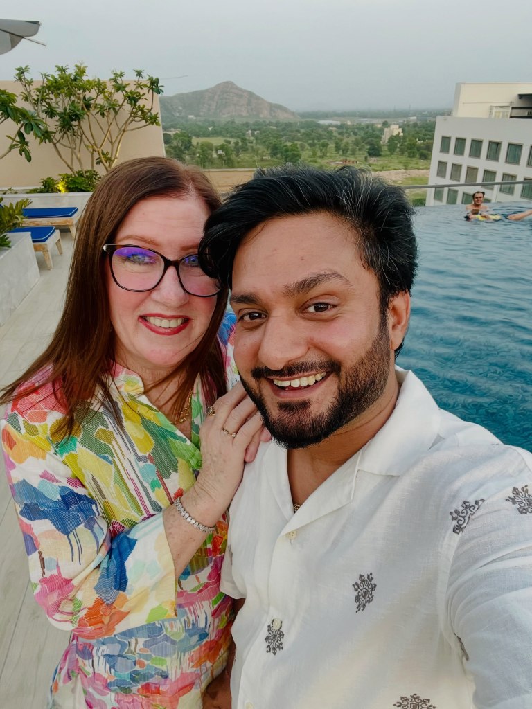 Jenny Slatten and Sumit Singh smiling for a selfie by a pool.