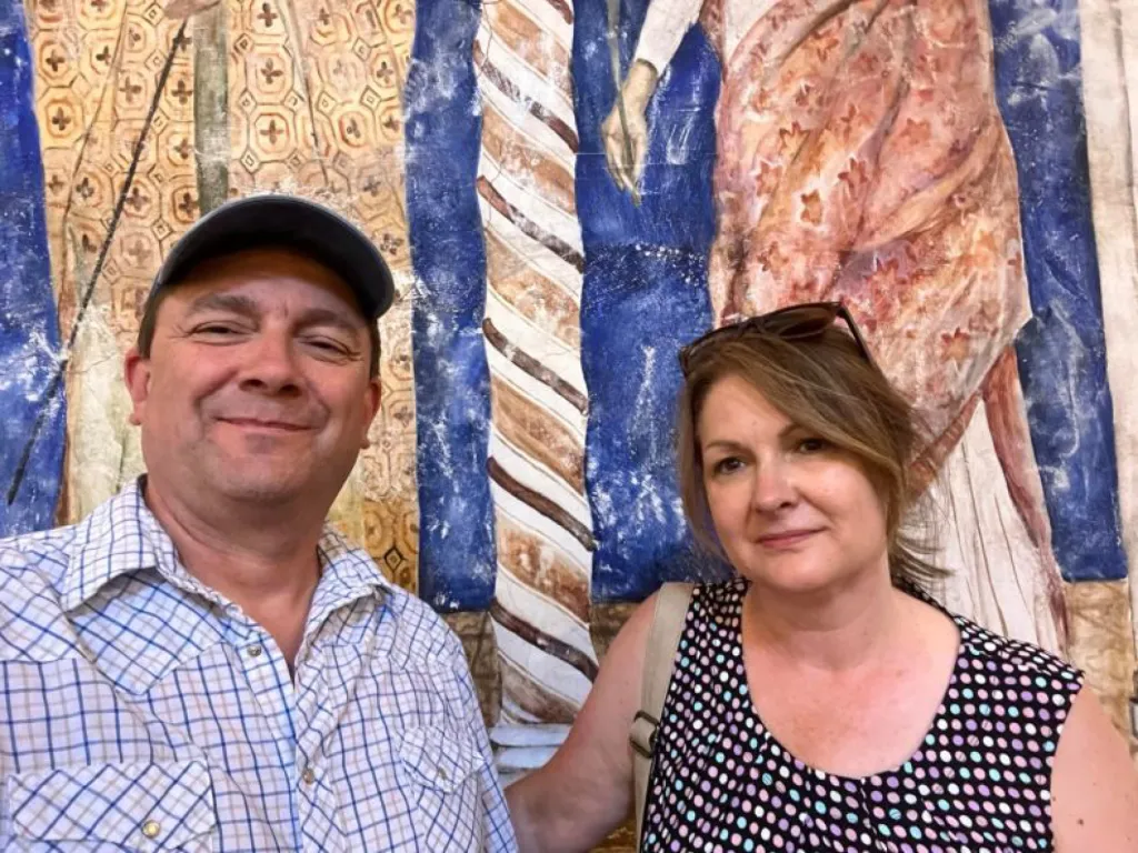 Troy Jackson and his cousin Lana Pelletier smiling in front of a colorful painted wall.