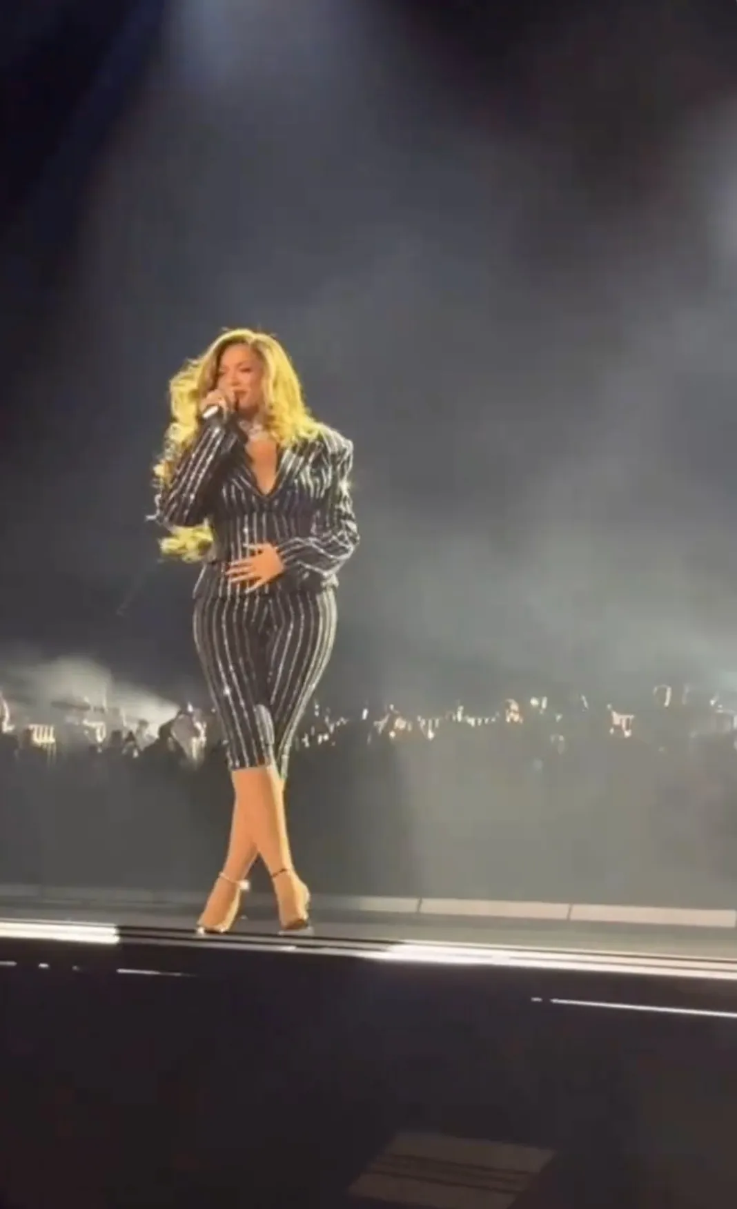 Beyoncé performing live on stage in a sparkling striped suit.
