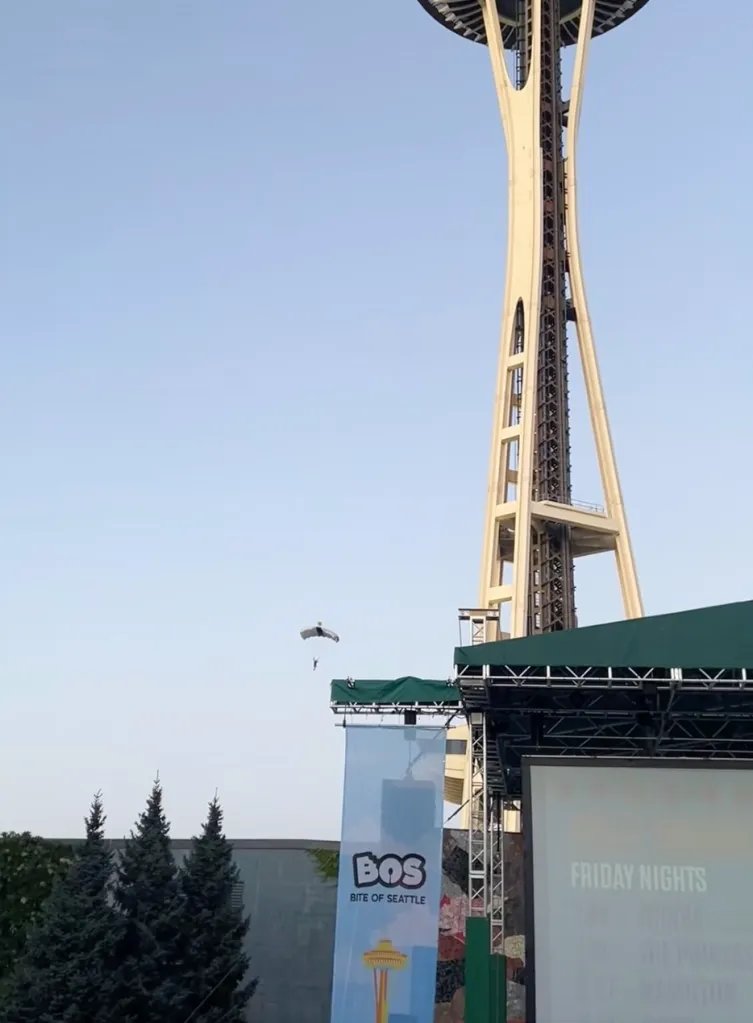 A person parachuting in front of the Space Needle.