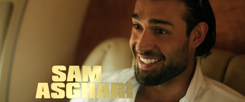 Sam Asghari smiling in a white shirt, with his name in gold capital letters on the left.